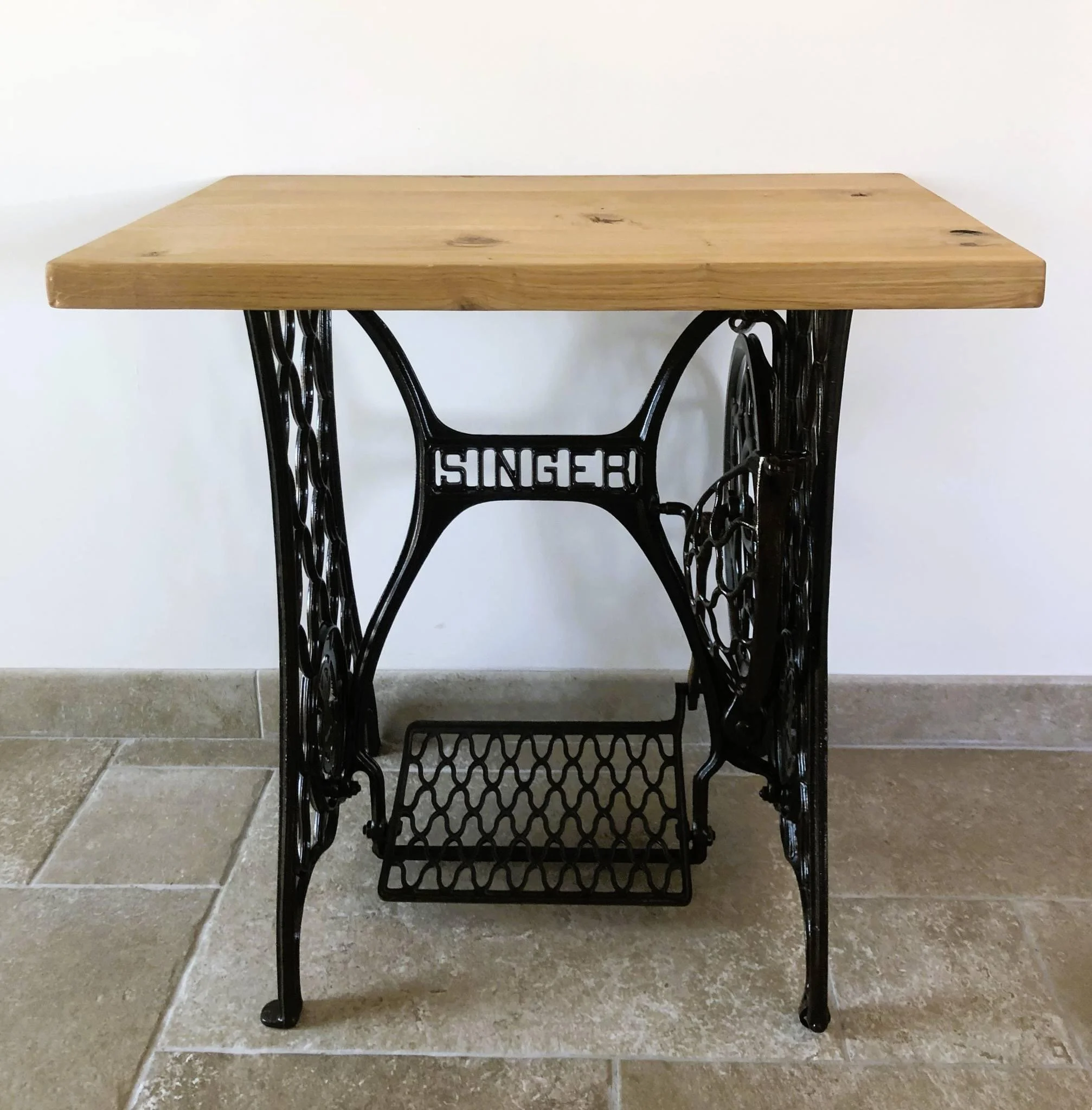 A vintage Singer sewing machine turned into a table with a wooden top.