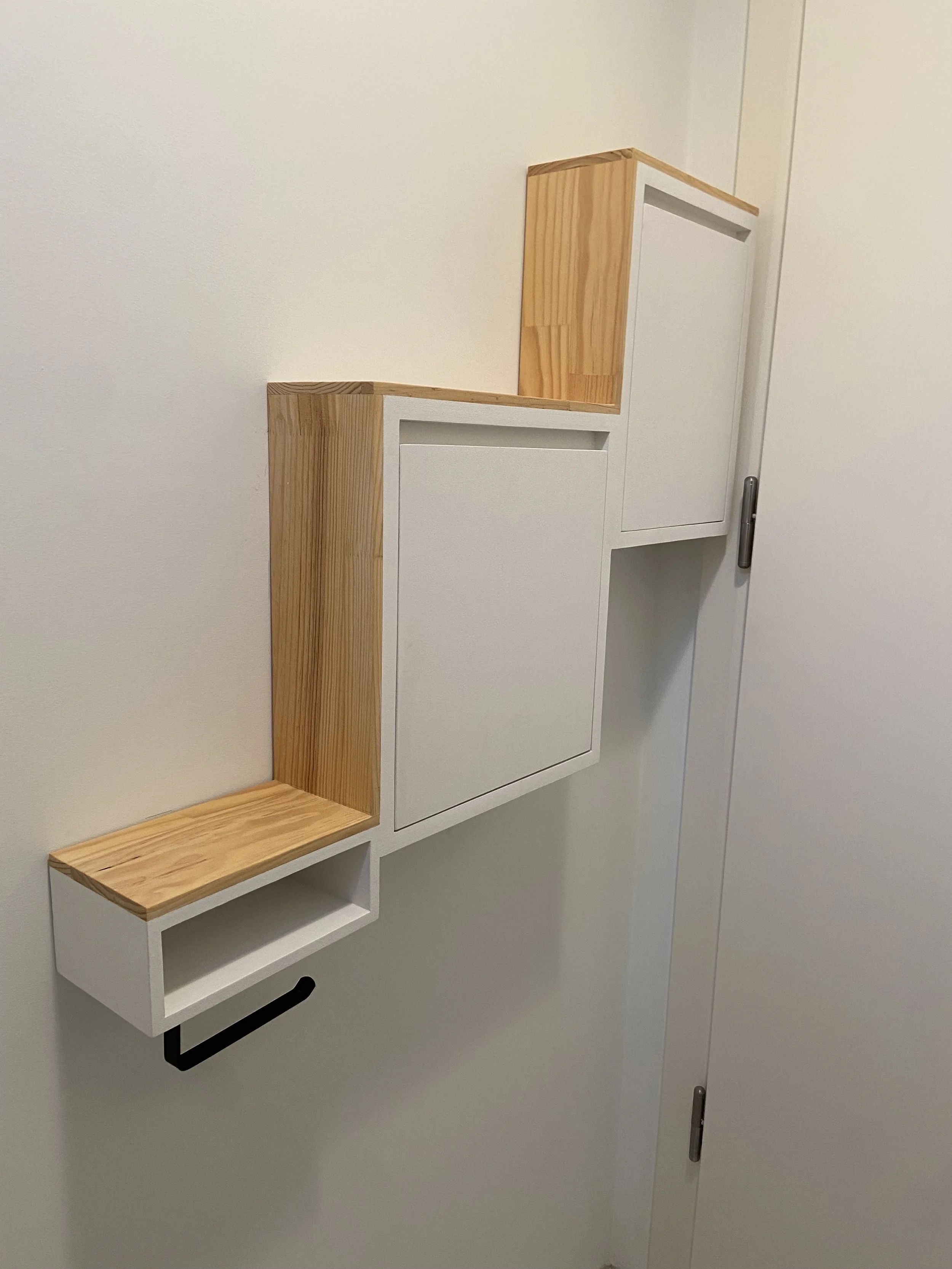 Wall-mounted storage with white and natural wood finish, designed with staggered rectangular compartments and a black handle.