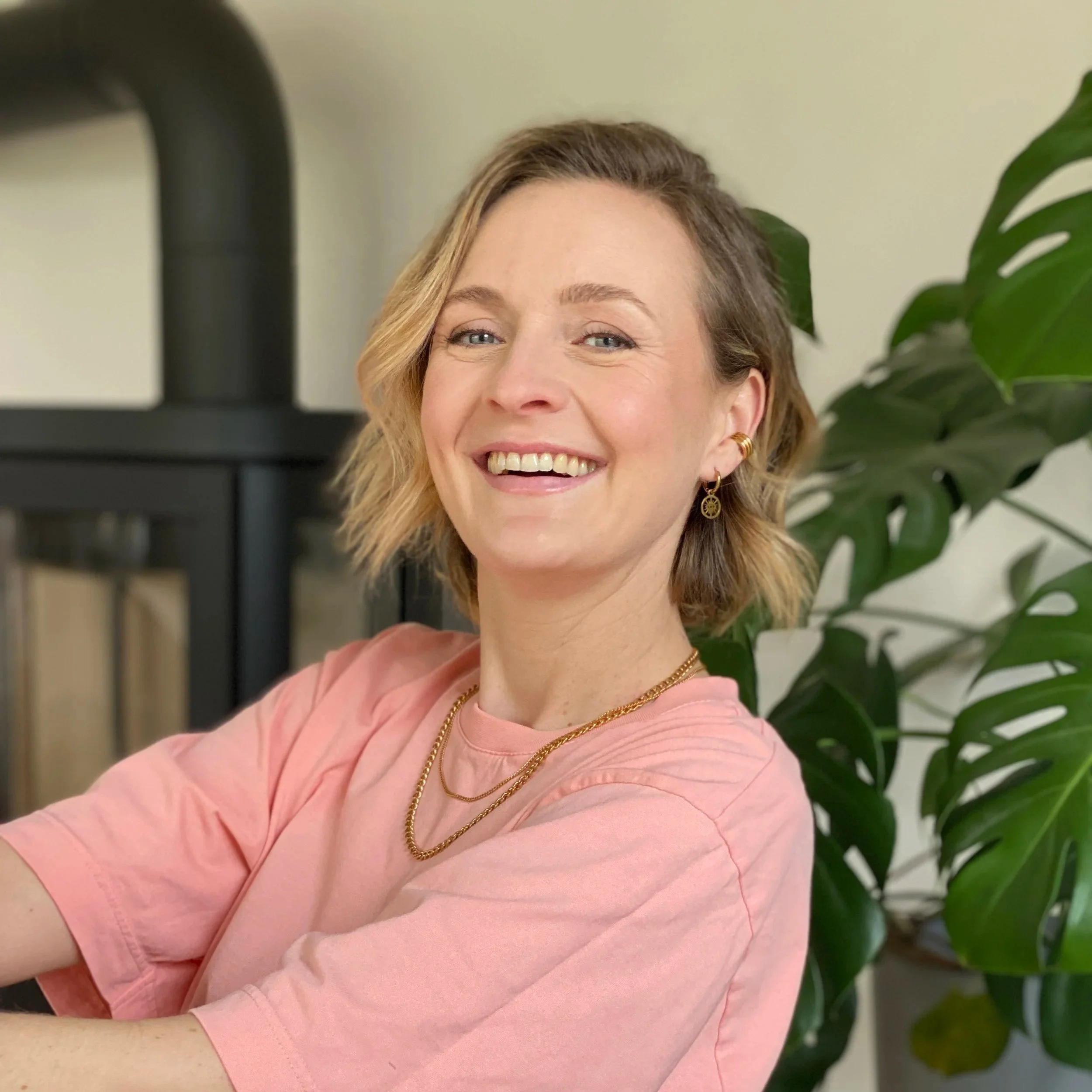 Sabrina Scholten, Gründerin von Studio Lune Interiors, lächelnd vor einer grünen Pflanze bei natürlichem Licht.