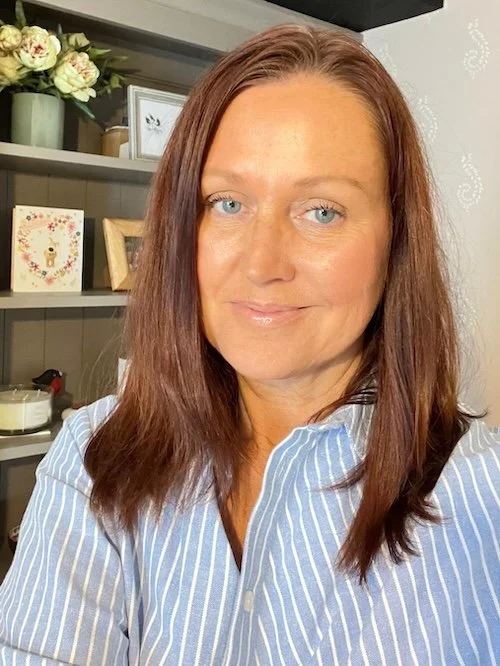Christie Barlow indoors with decorative shelves, flowers, and framed pictures in the background.