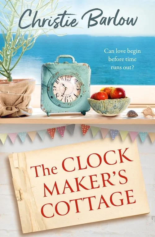 Book cover for "The Clock Maker's Cottage" by Christie Barlow, featuring a vintage kitchen scene with a teal clock, apples in a bowl, a potted plant, and colourful bunting against a seaside backdrop.