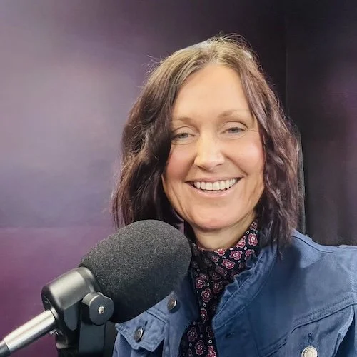 Christie Barlow smiling in front of a microphone on a purple background.