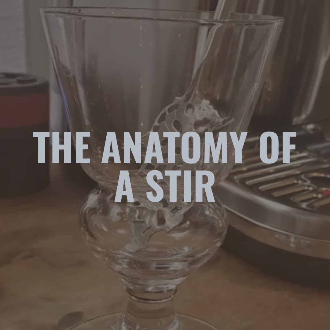 Close-up of a glass stir stick in a crystal glass with the overlay text 'The Anatomy of a Stir'.