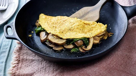 Omelet with mushrooms and spinach in a black skillet