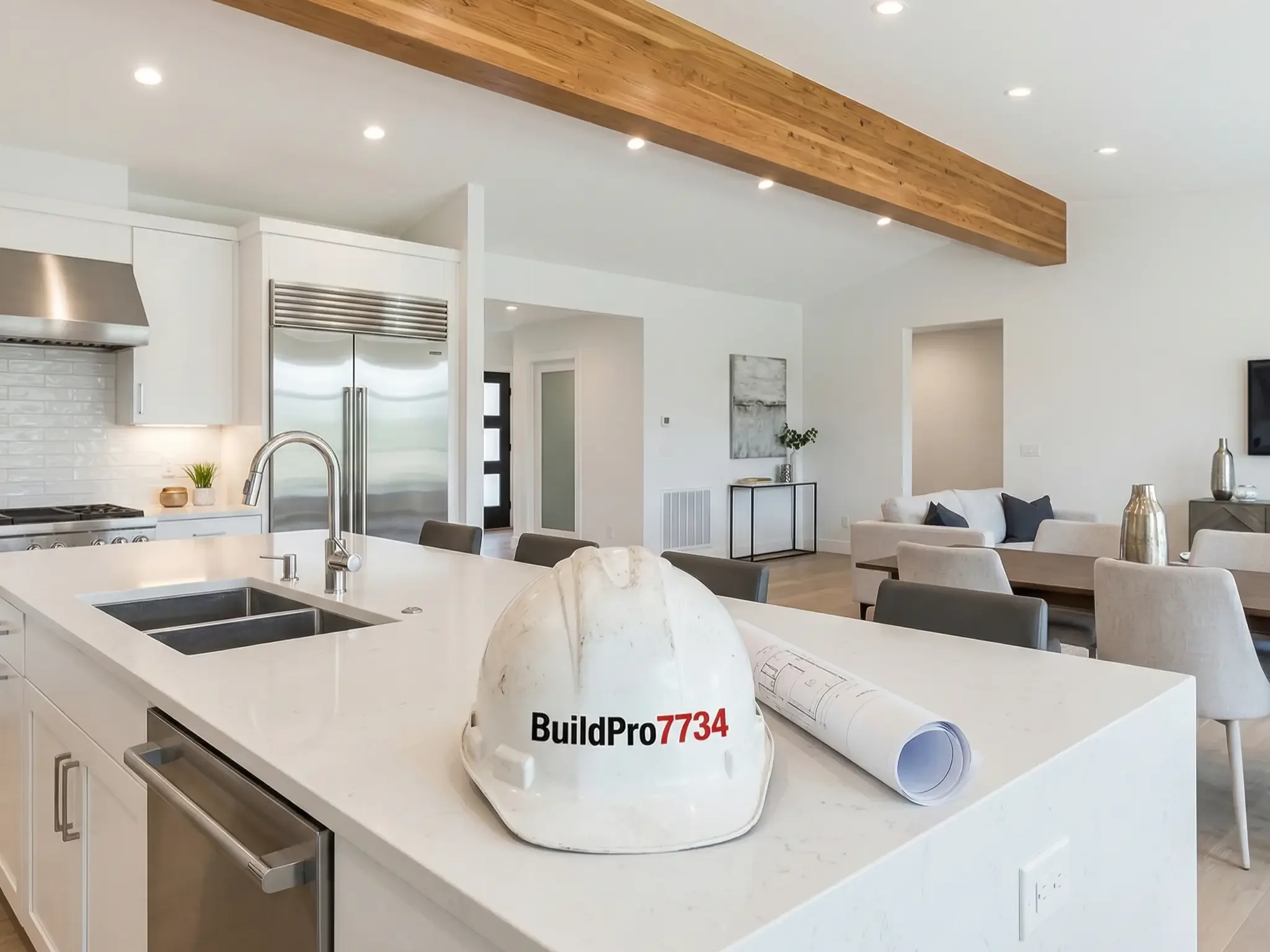 Modern open-concept kitchen and living room with white cabinetry, stainless steel appliances, a white island with a blueprints and a construction helmet labeled BuildPro 7734, and a living area with neutral furniture and decor.