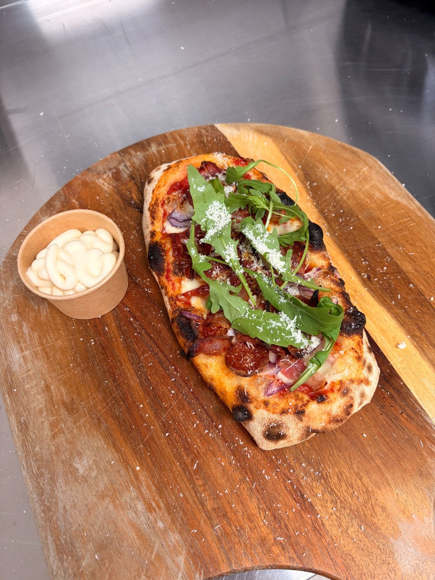 GBoF pizza with rocket and shaved cheese, served on a wooden board with a dip
