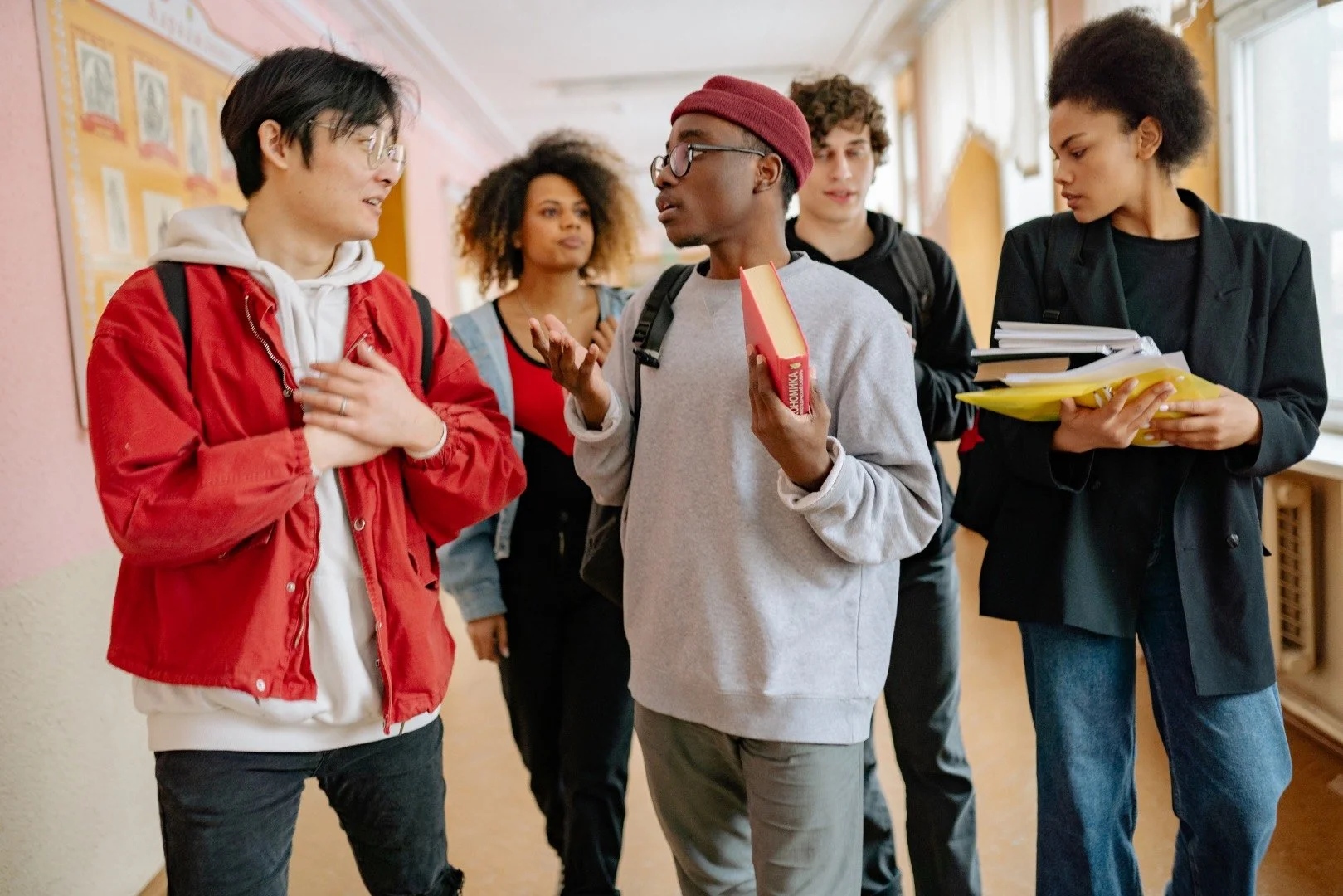 A group of five students discussing with each other after a class.