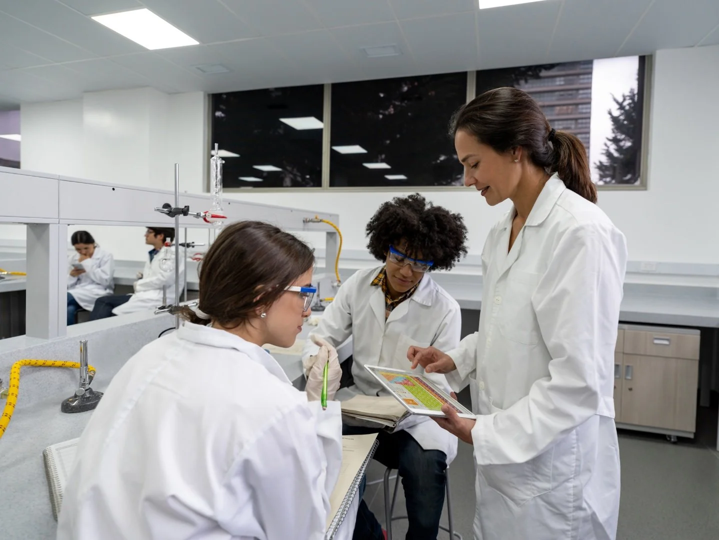 Two student with their teacher while performing a scientific experiment in a lab.