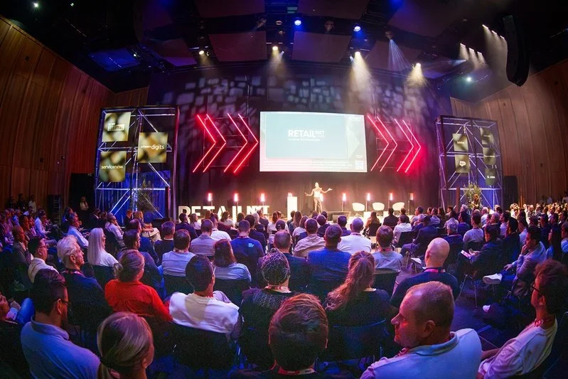 Voll besetzter Saal im VILCO Bad Vilbel während der RetailNXT 2026, Blick von hinten auf die Bühne