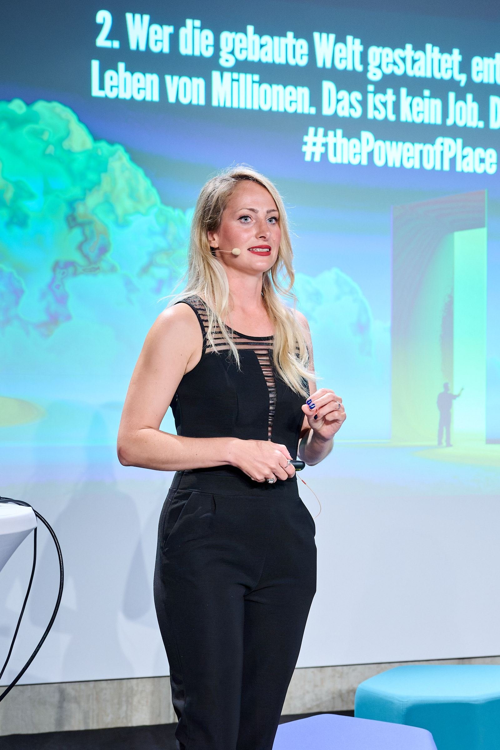 Katharina Aguilar vor der Folie zur gebauten Welt mit dem Hashtag The Power of Place