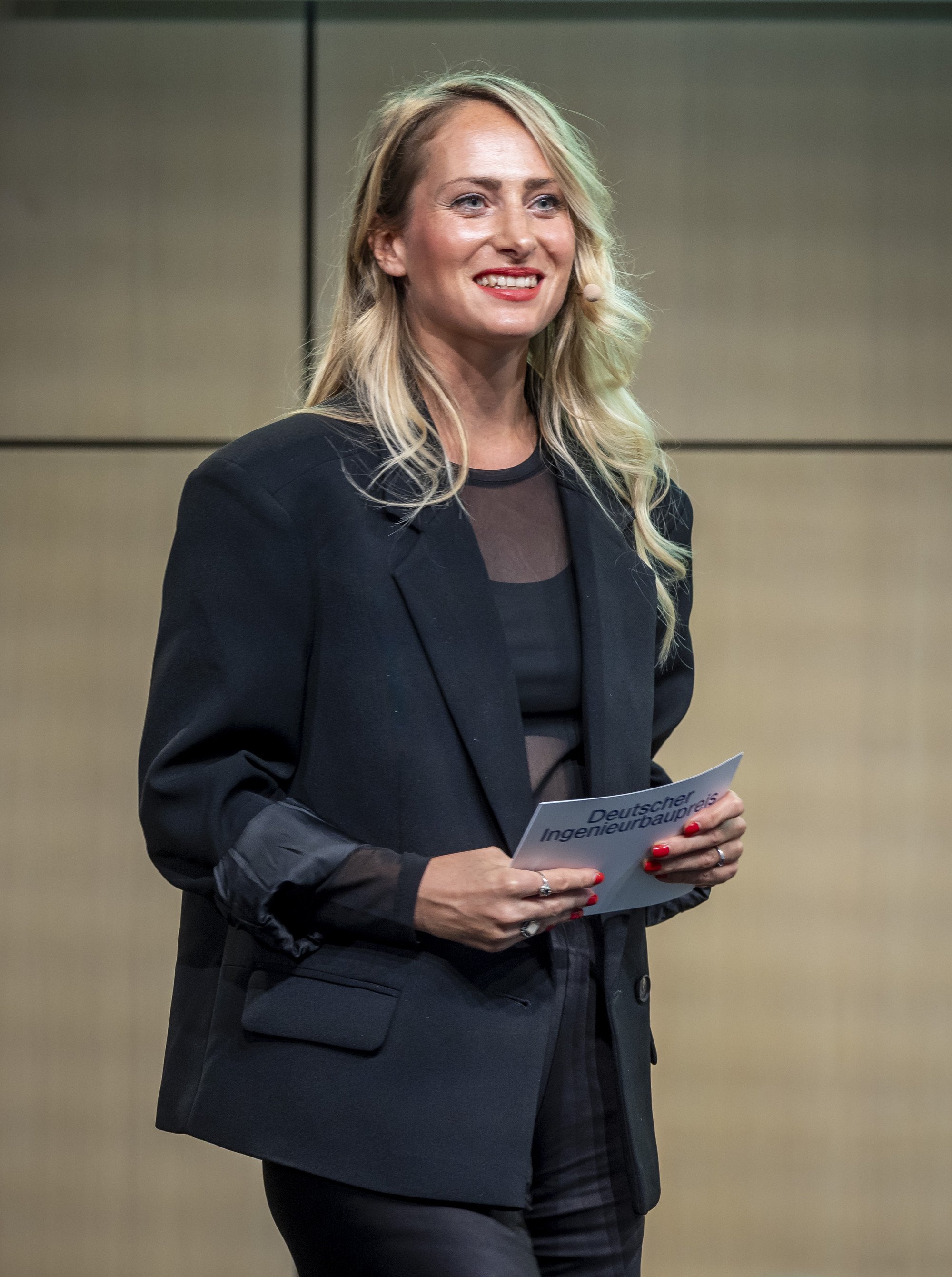 Moderatorin Katharina Aguilar mit Moderationskarten auf der Bühne beim Deutschen Ingenieurbaupreis 2026 in Berlin