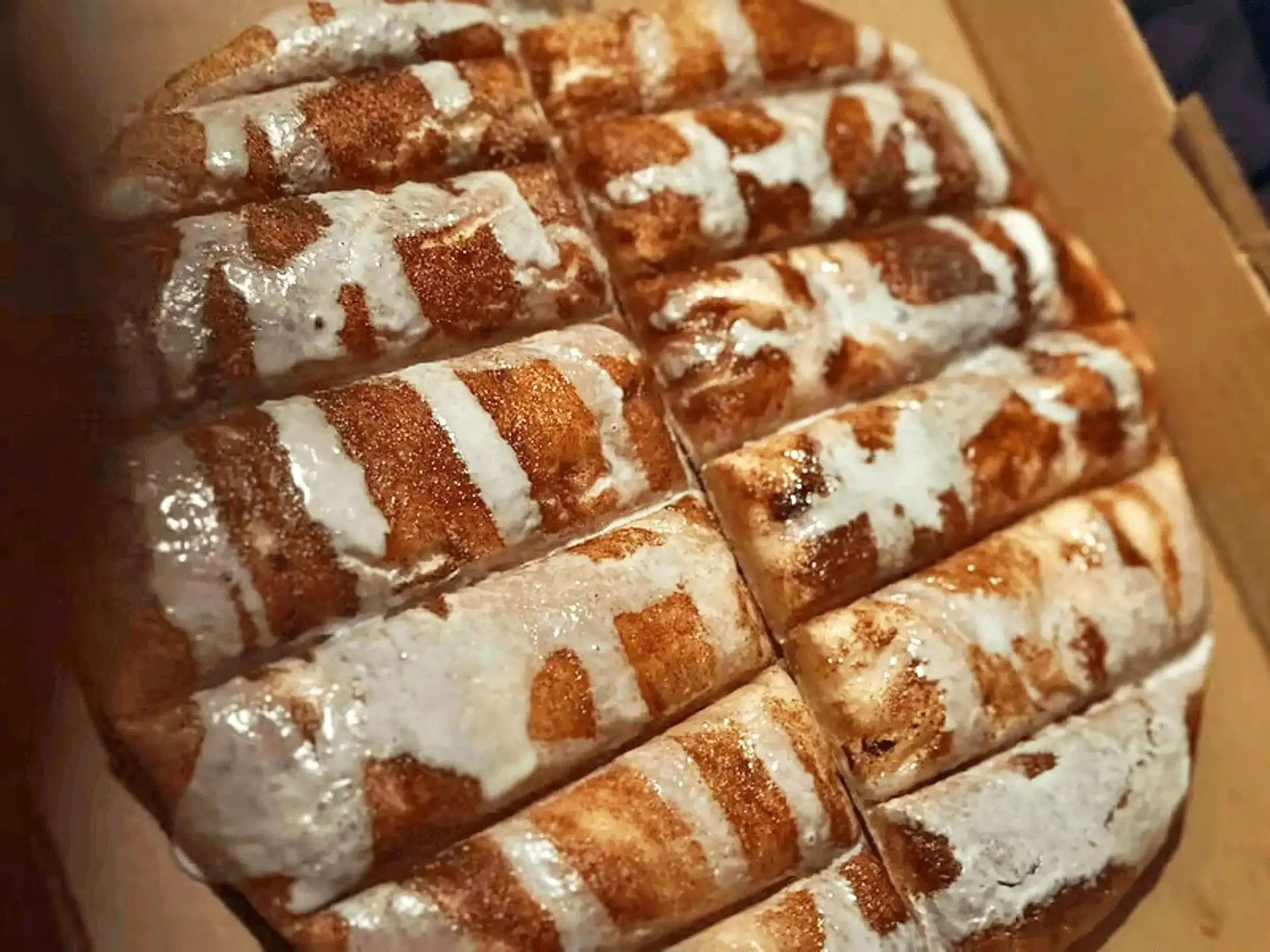 A close-up of a pizza with a thick, golden crust topped with melted cheese and drizzle of white sauce.