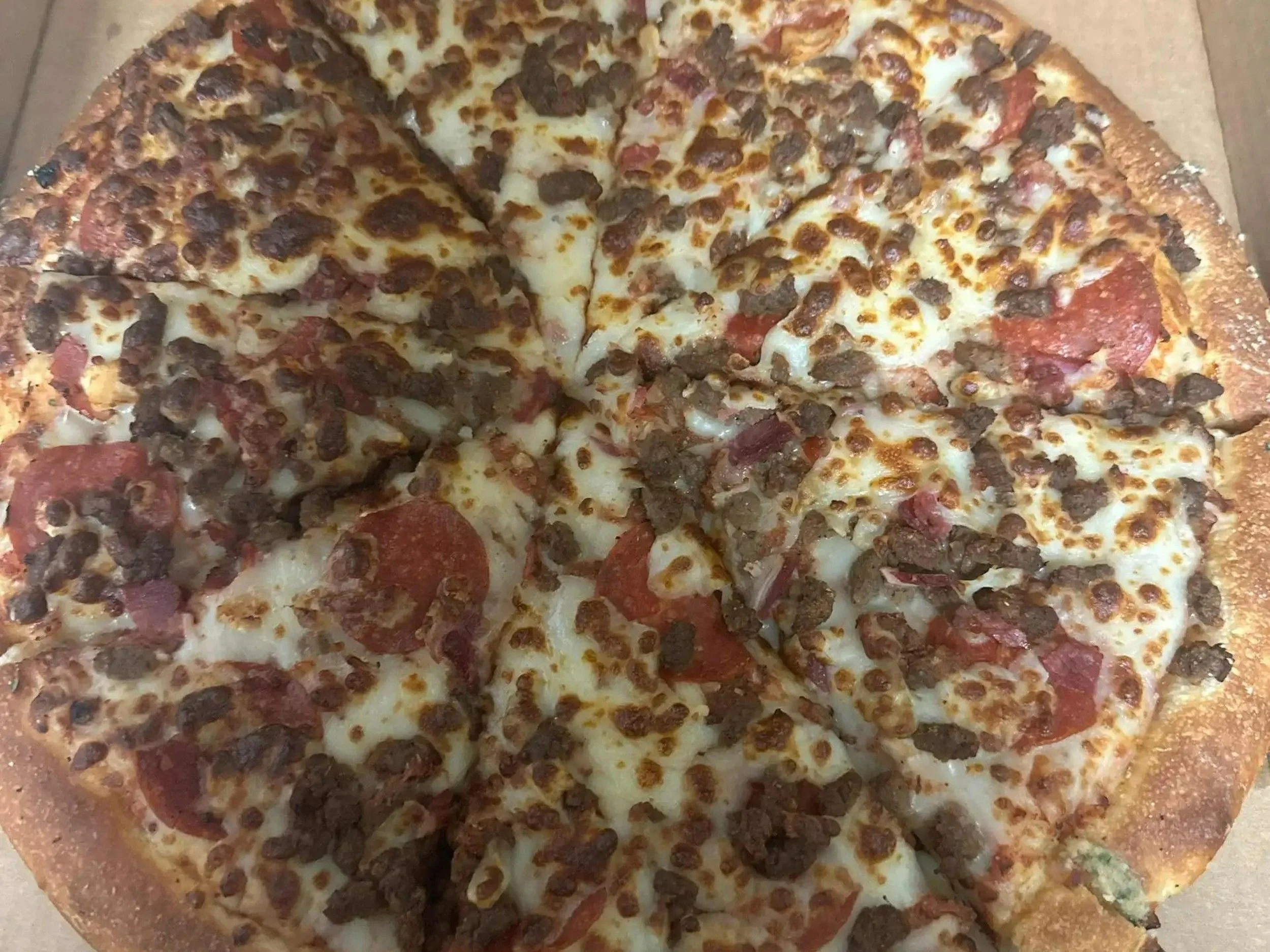 A pizza topped with sausage, pepperoni, and mozzarella cheese in a pizza box.