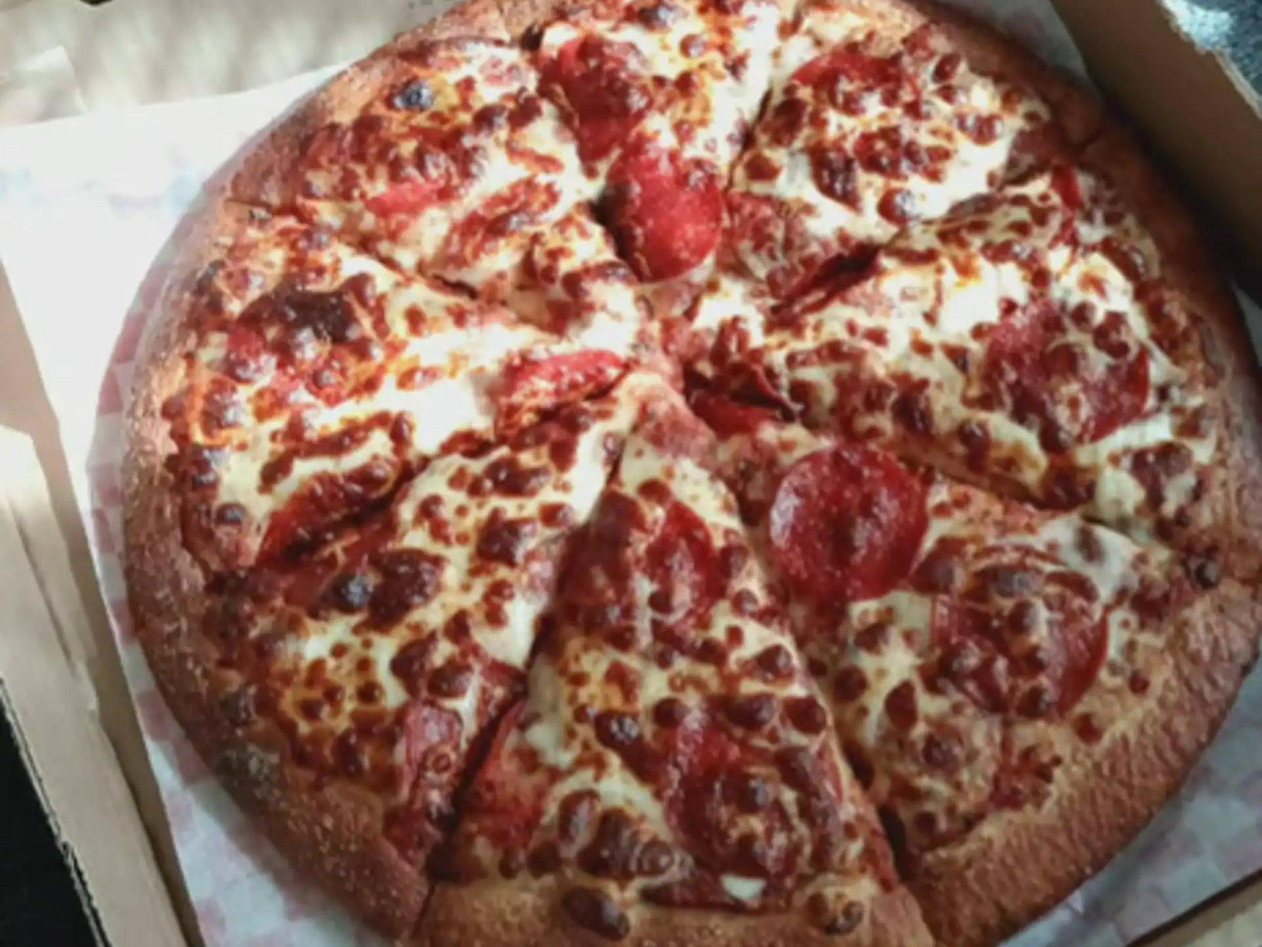 A large pepperoni and cheese pizza in a cardboard box.