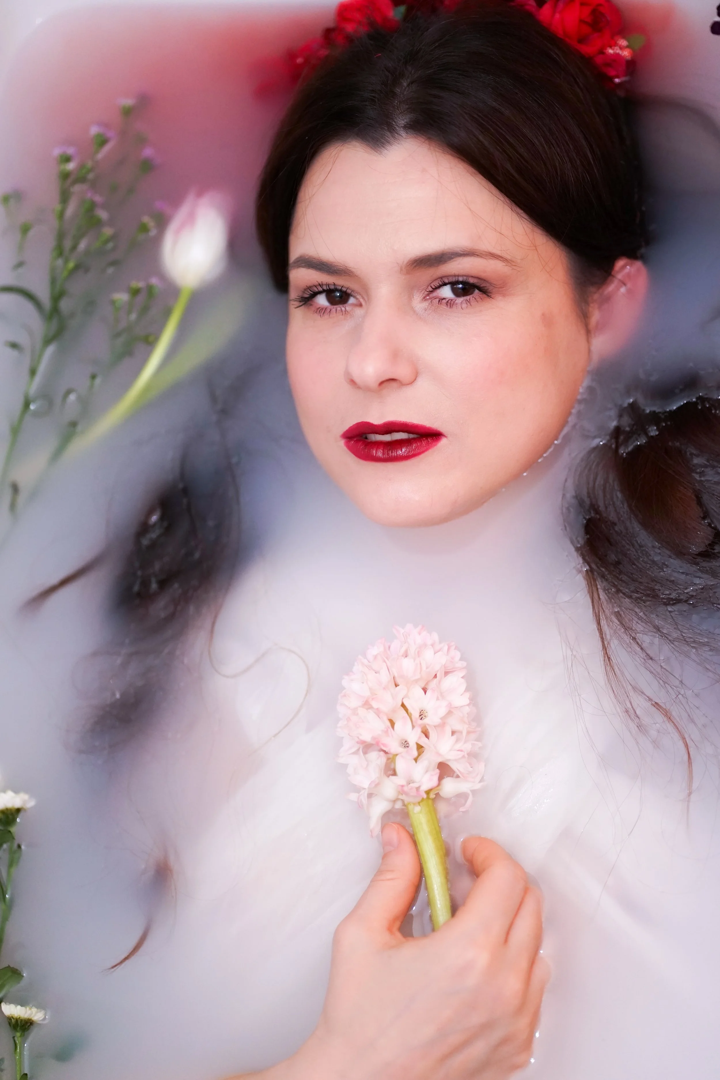 Fine art portrait photo of a woman in a milky bath with flowers, South Wales Bridgend photography.
