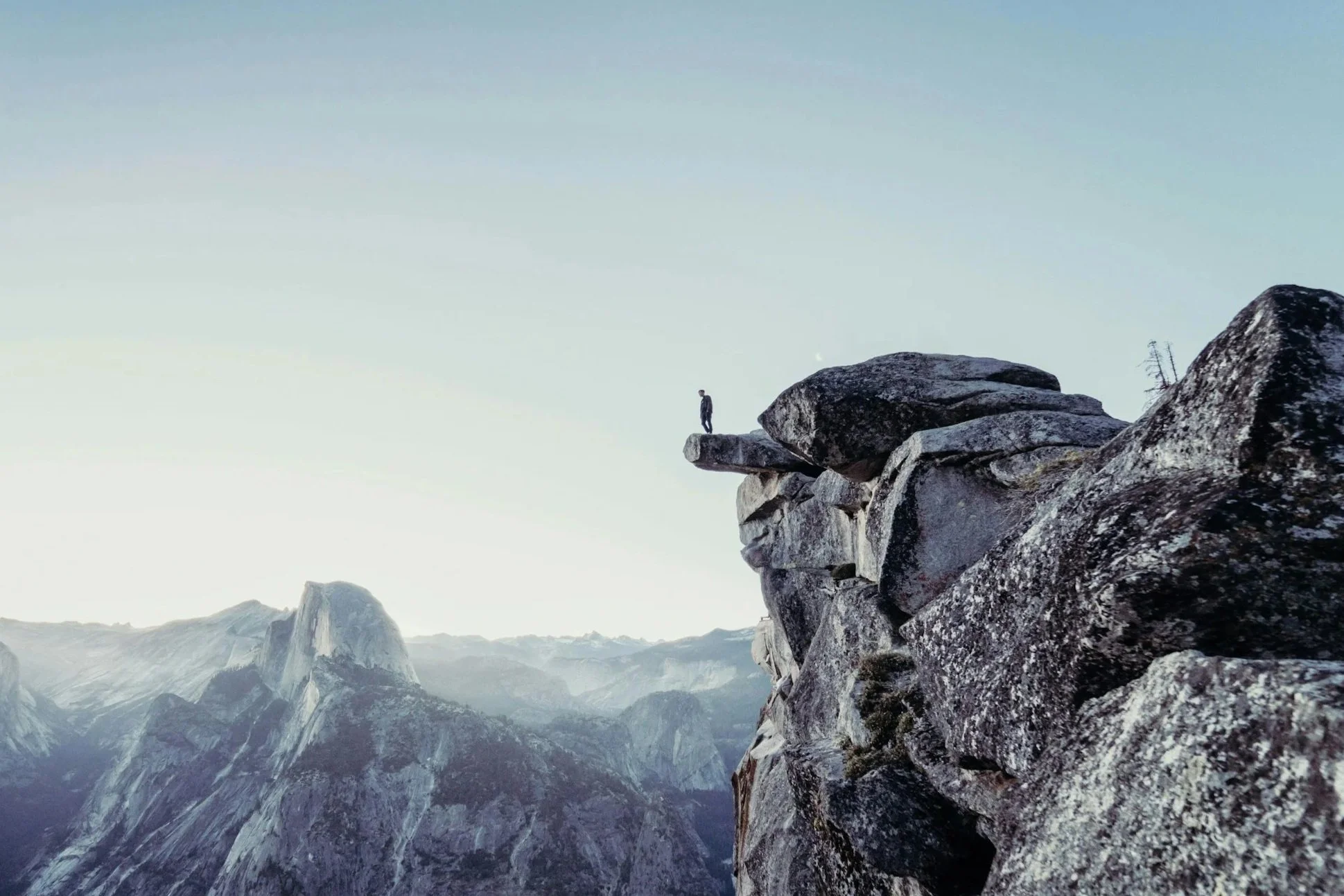 person standing on cliff overlooking mountains representing risk and protection planning in financial strategy