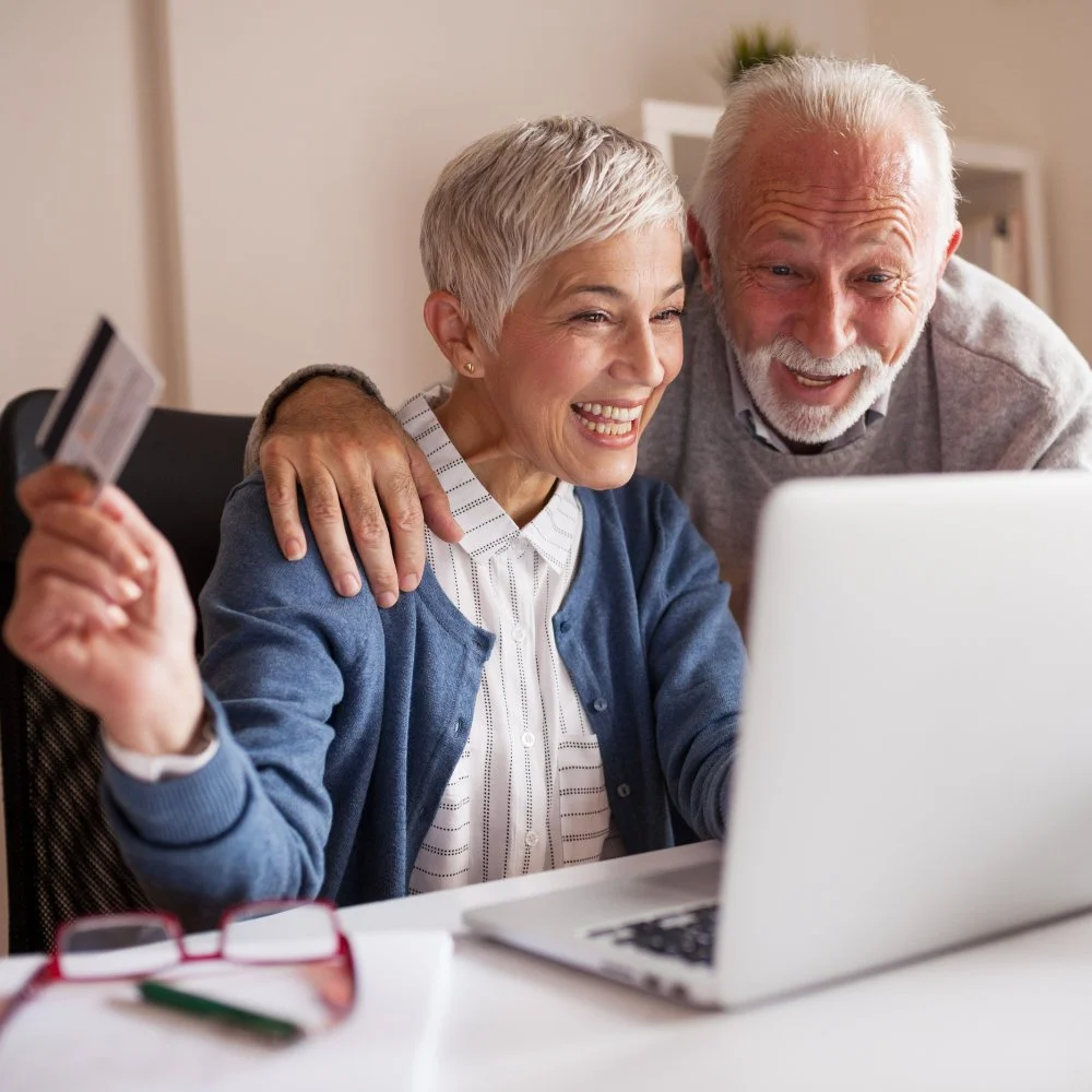 Couple happily booking a Sir Painter service online with a credit card and laptop