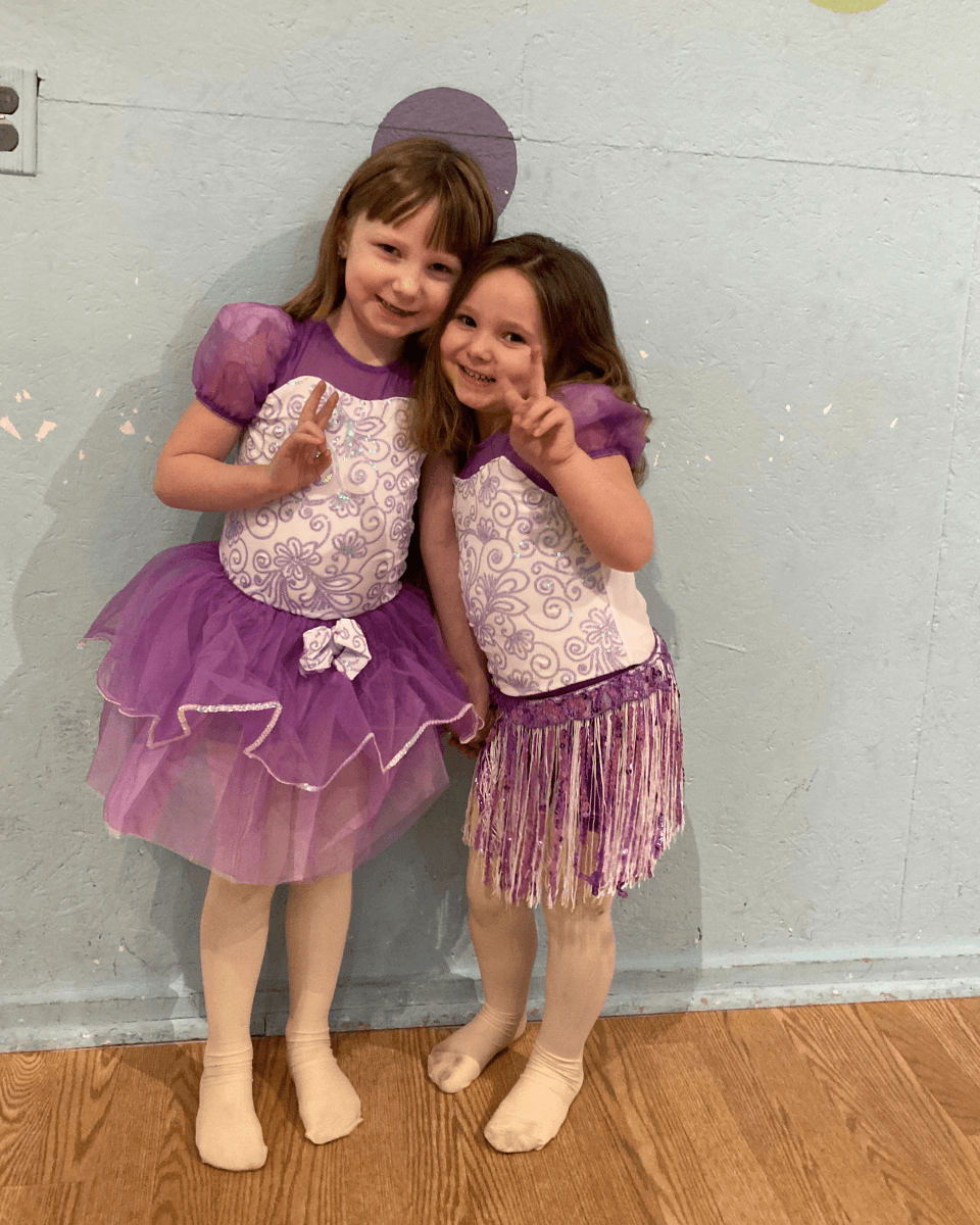 Two dancers in purple costumes posing after dance class