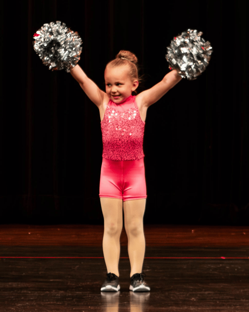 Preschool dancer on stage with pink costume and silver poms
