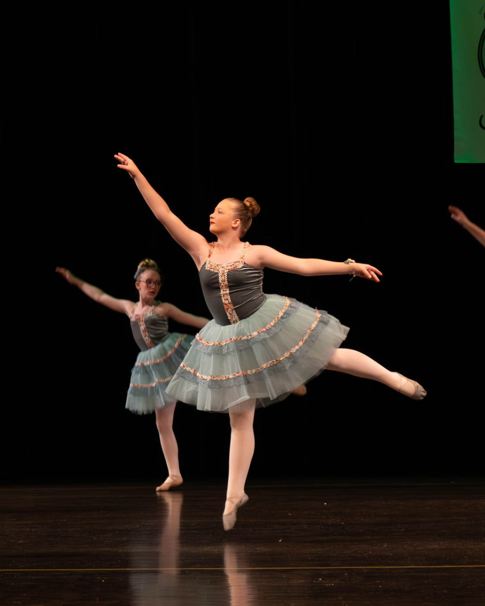 Two ballet dancers in green costumes performing at spring recital
