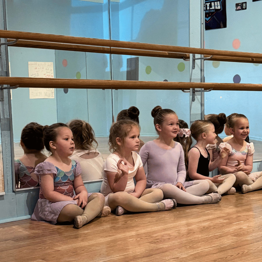 Group of young dancers in dance class seated on the floor