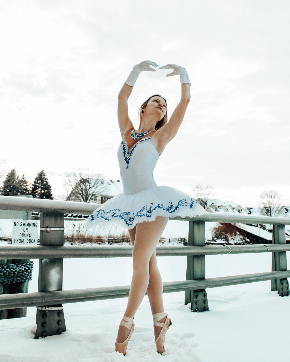 Pointe dancer in white costume posing outside in the snow
