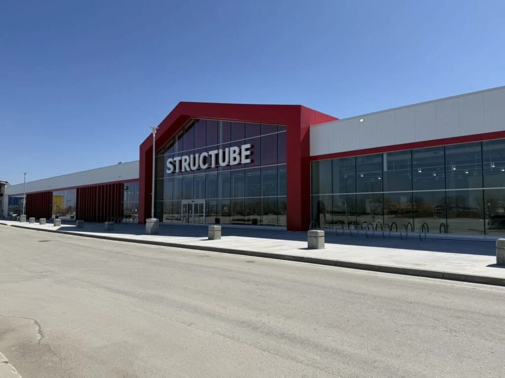 Exterior of a building with red and white facade, large glass windows, and a sign that reads 'STRUCTUBE'.