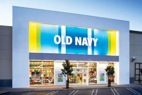 Exterior of an Old Navy clothing store with large sign, glass doors, and two potted trees outside.