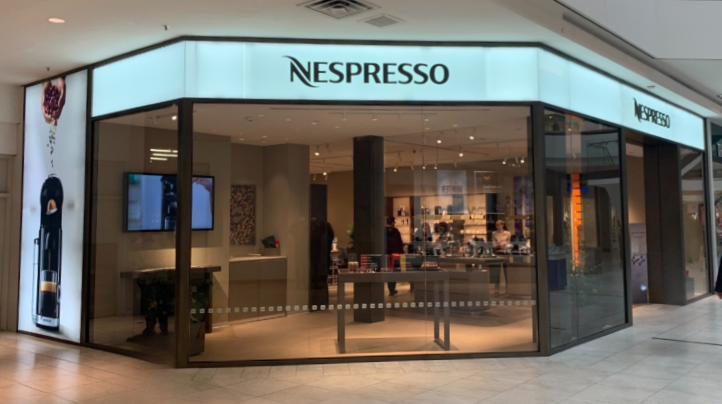 Nespresso coffee shop inside a shopping mall with large glass windows and illuminated signage.