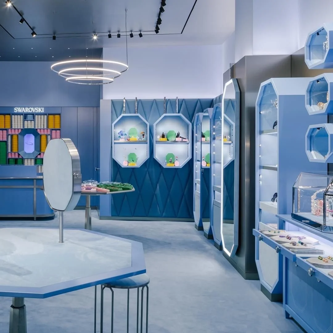 Luxurious jewelry store with blue accent walls, display cases, and modern lighting.