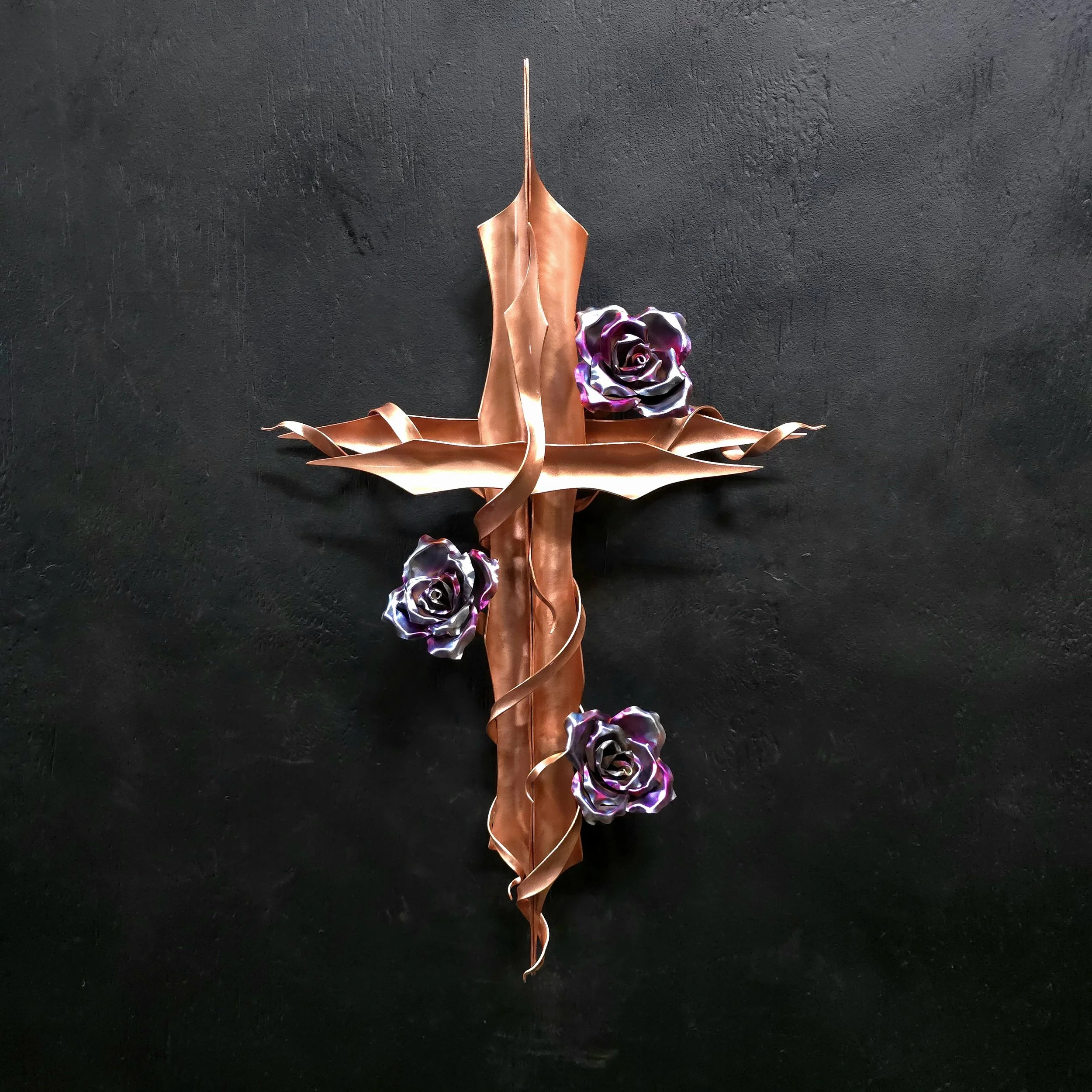 A decorative metal wall art piece with a vertical rose and leaf design, accompanied by three metallic purple and black roses, mounted on a black wall.