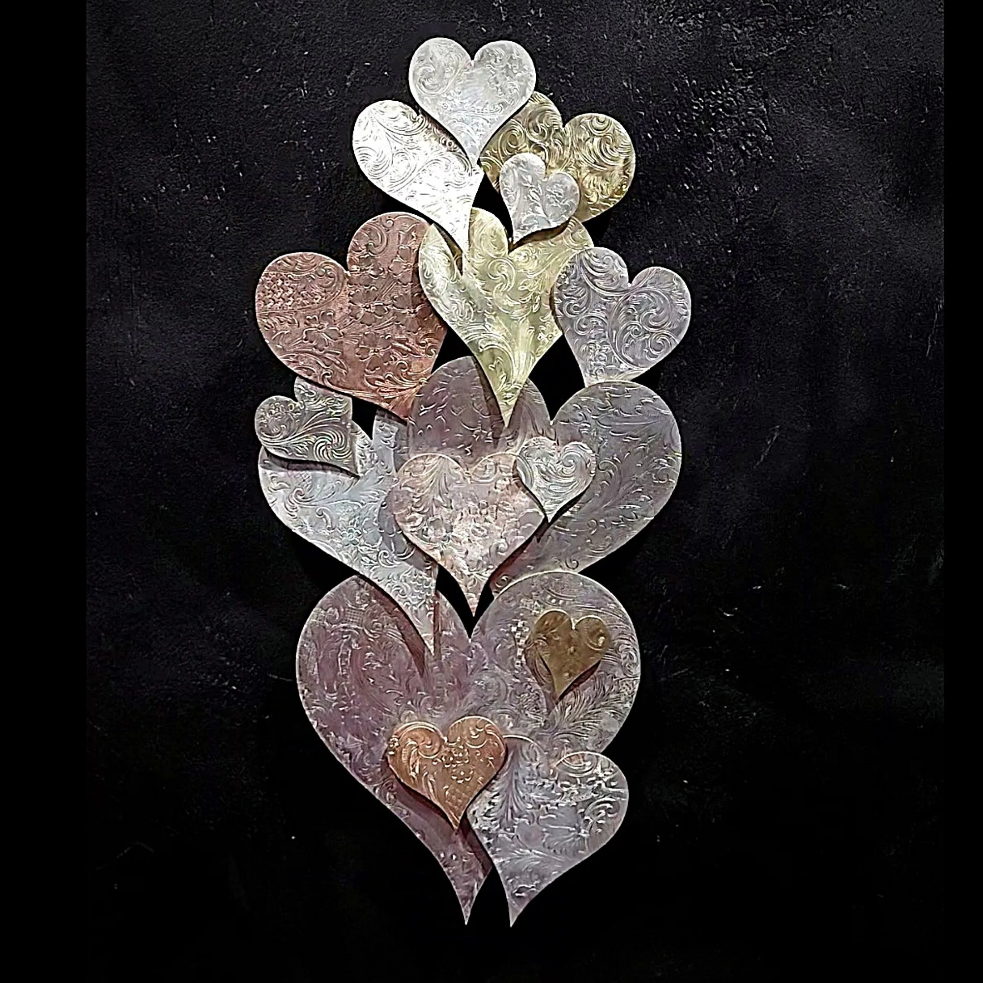 Vertical arrangement of overlapping Hearts in multiple sizes, created with copper and brass silver-plate with embossed scrollwork and a high gloss finish.