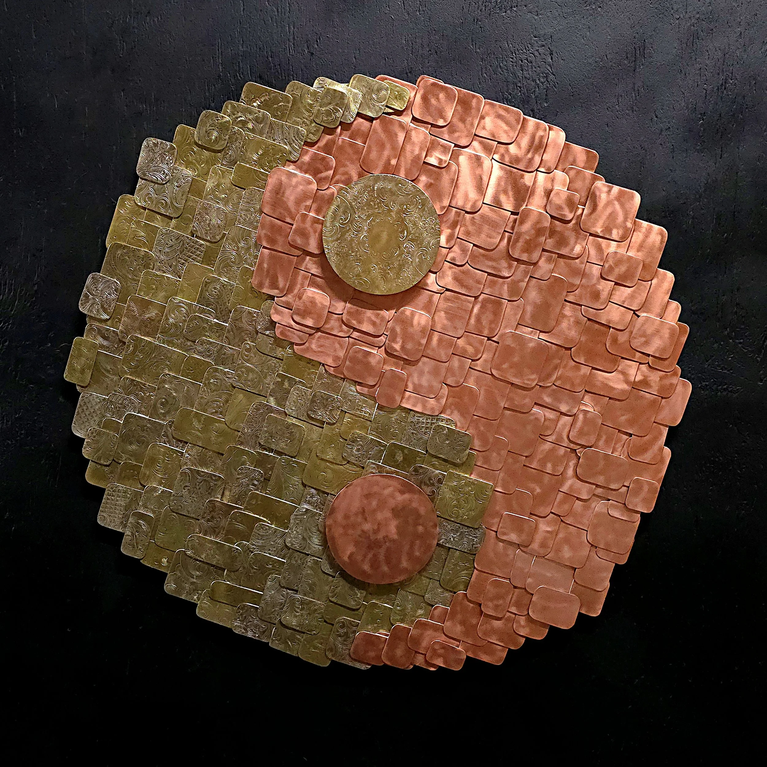 An intricate wall art piece made of overlapping rectangular tiles in gold and pinkish tones, with two large textured circular elements.