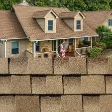 A house behind a tall brick wall with a porch, an American flag, and green trees.
