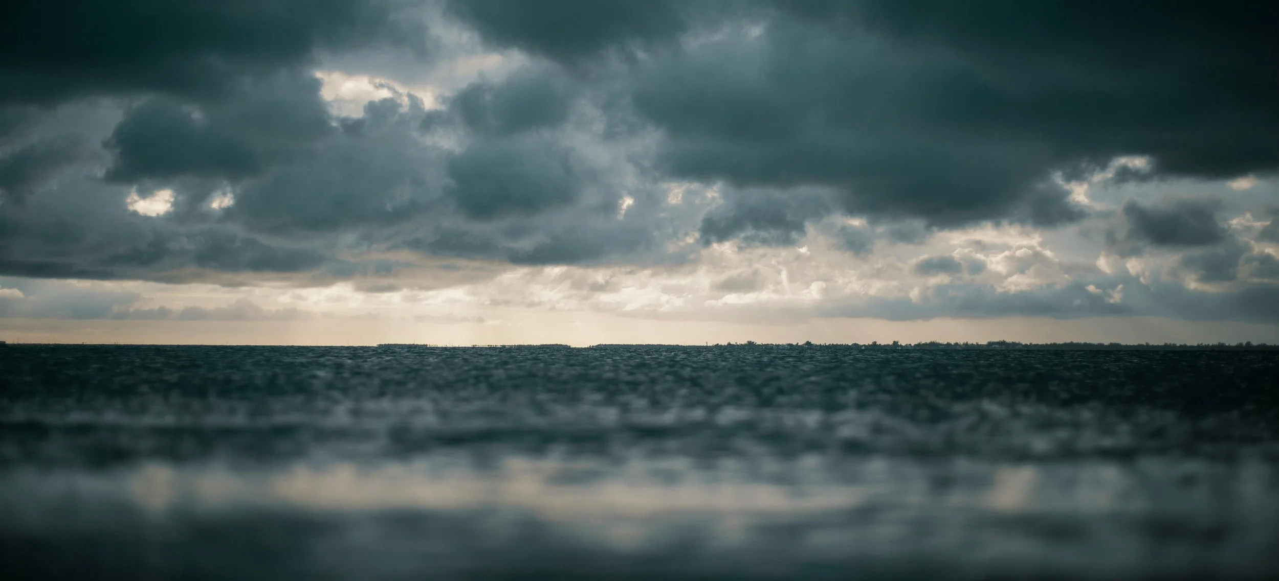 A wide shot of a body of water with dark, cloudy skies above, suggesting an approaching storm or overcast weather.
