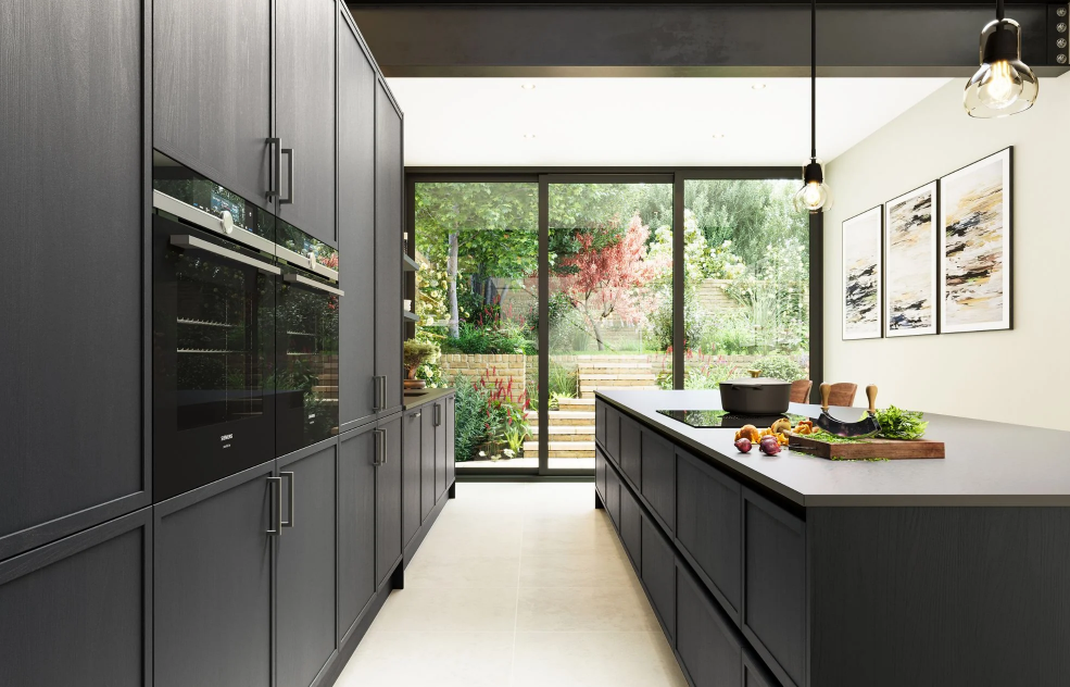 Modern kitchen with dark cabinets, an island with a cutting board and vegetables, and large glass sliding doors opening to a lush garden.
