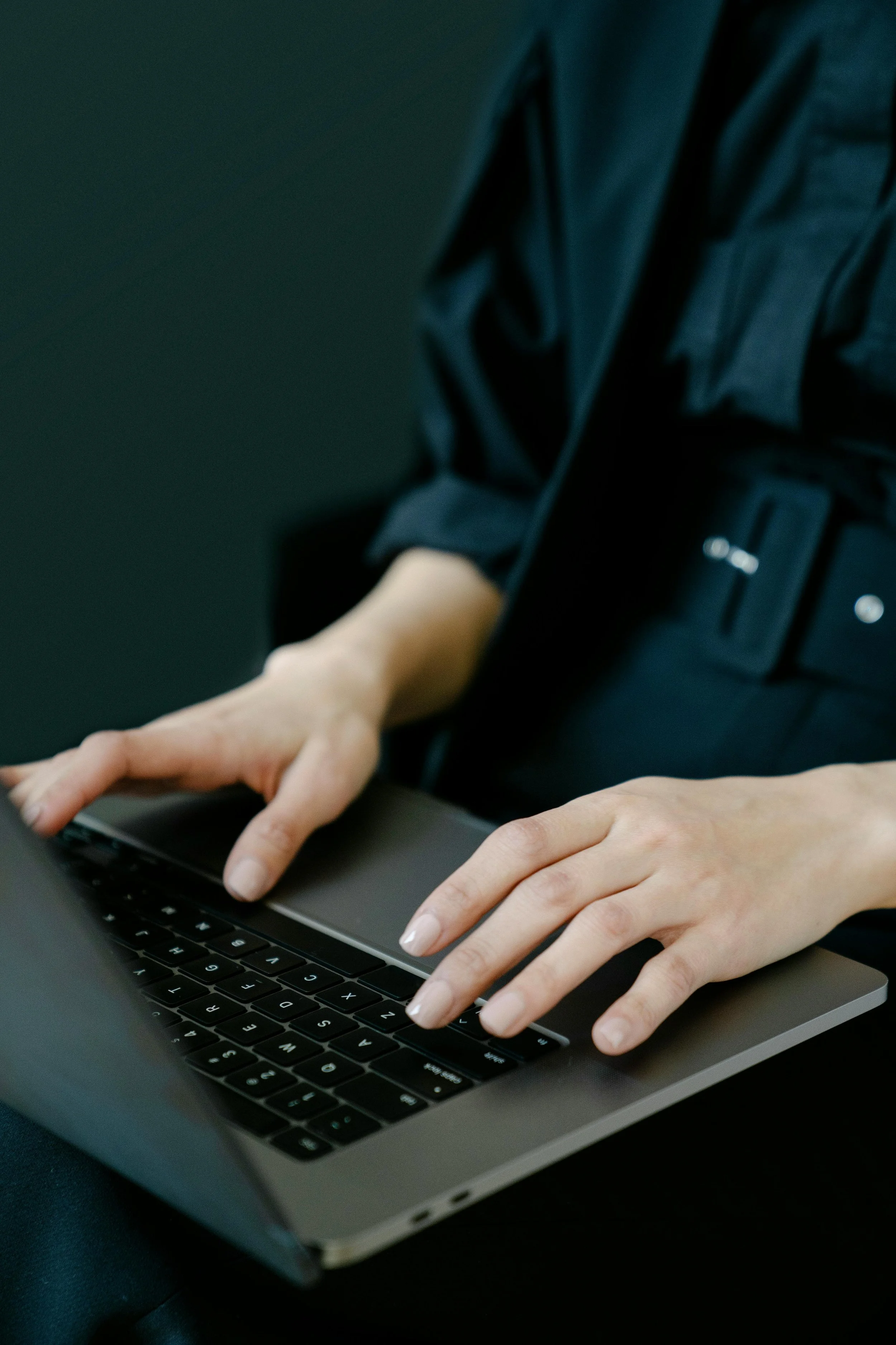 Close-up of a person typing on a laptop keyboard.