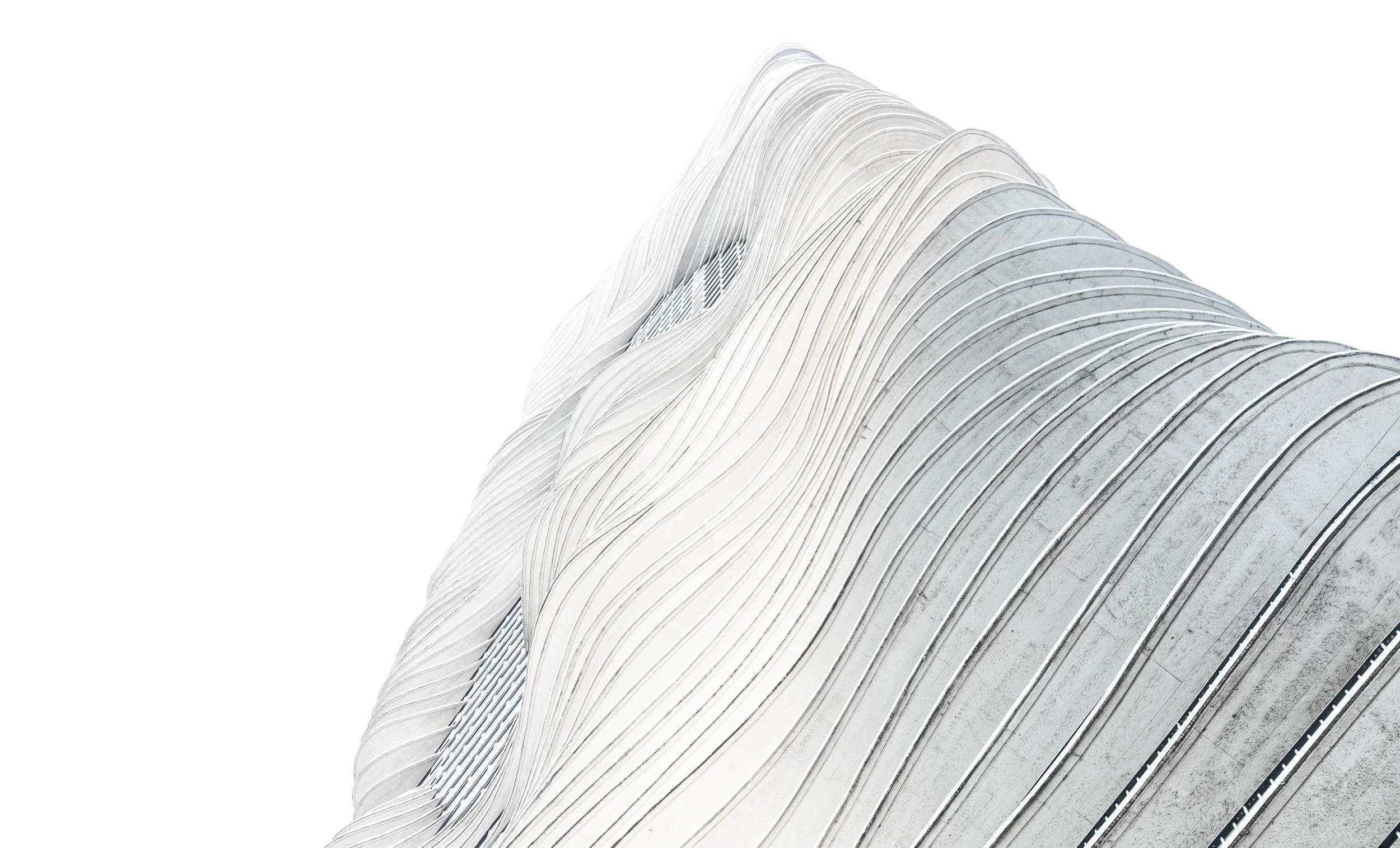 Modern architectural building with flowing, curved white facade and vertical lines, against a white background.