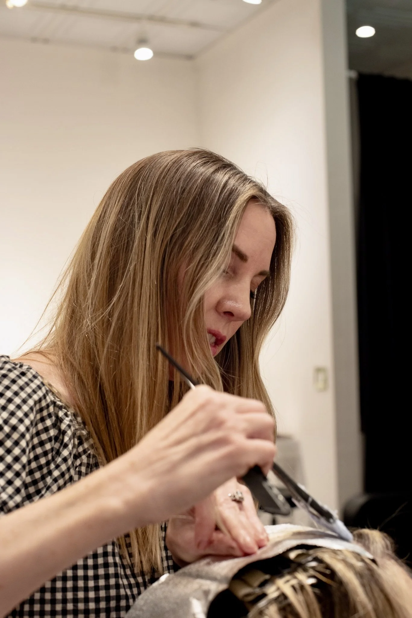 A woman with long blonde hair getting her hair cut or styled in a salon.