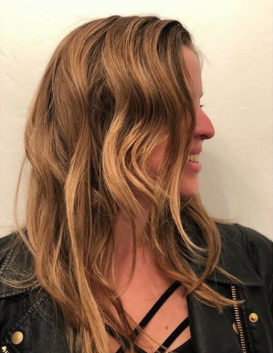 A woman lying down with her eyes closed, having her eyebrow shaped or tattooed by a professional in a beauty clinic or salon.