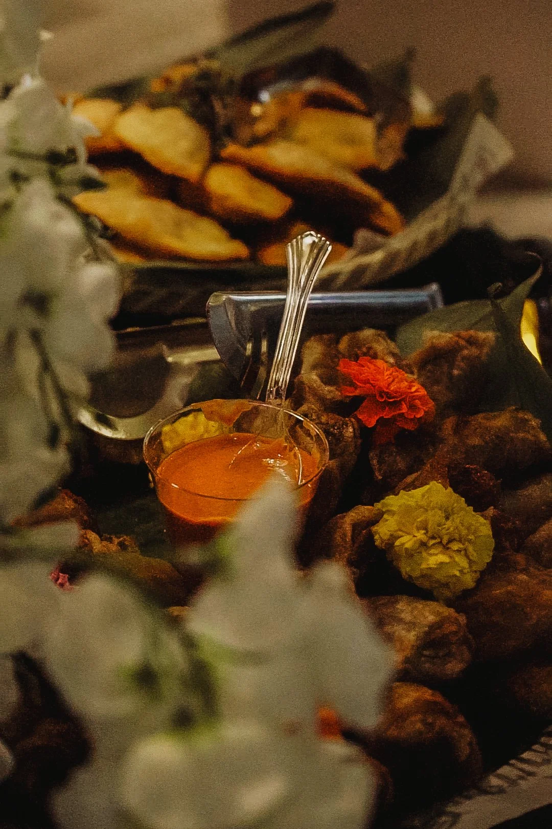 Plate of fried chicken with flowers and a small bowl of dipping sauce, with potato wedges in the background.