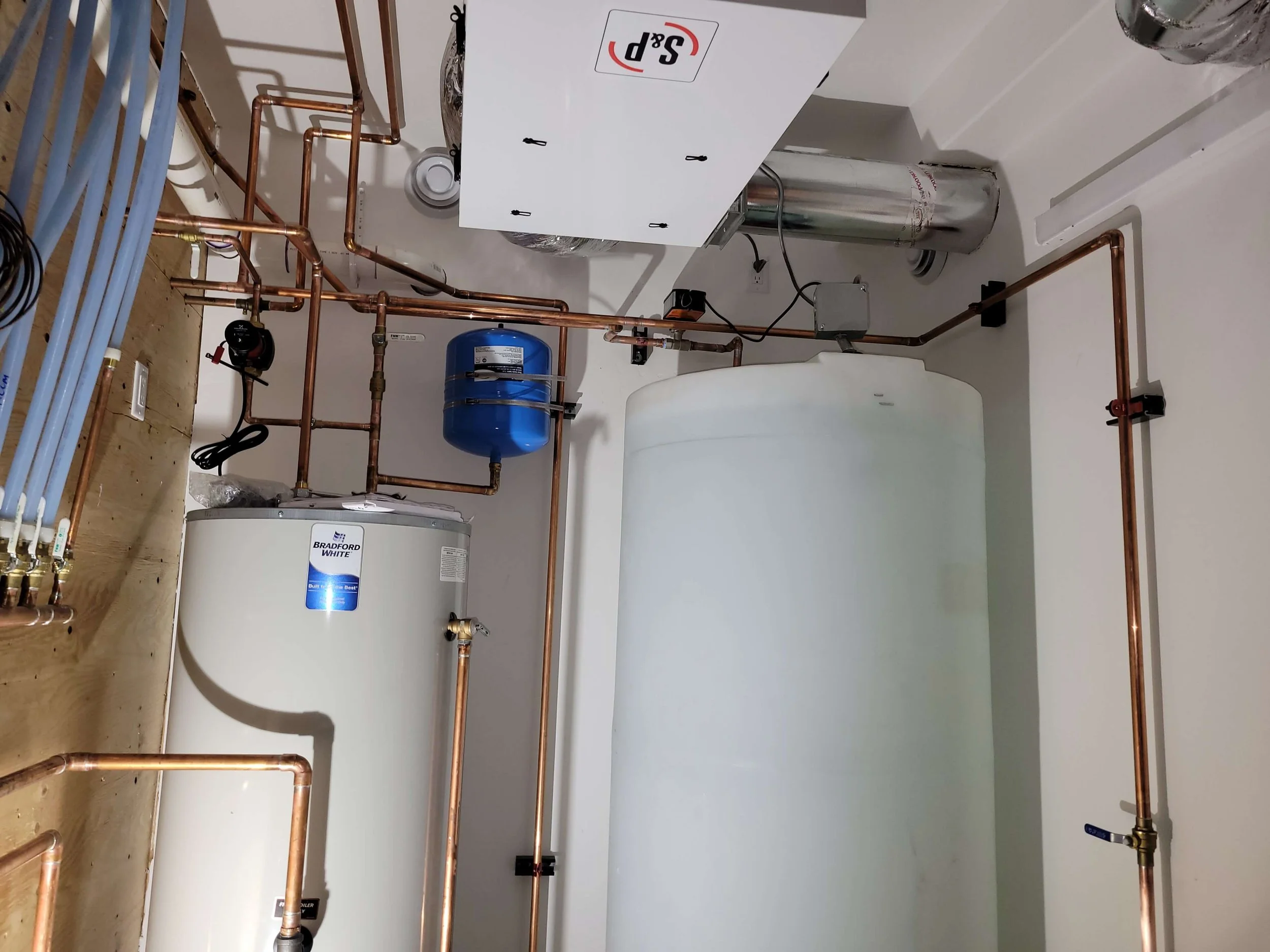 Basement utility room with water heater, pipes, and tank