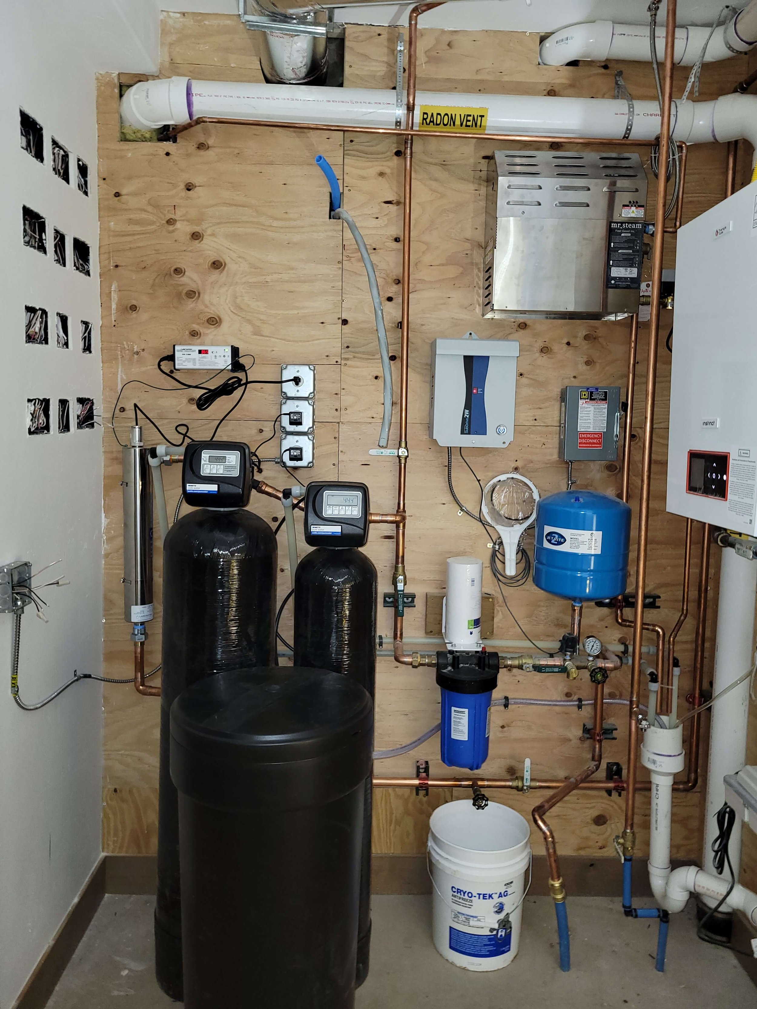 Basement utility room with radon vent, water filtration system, pipes, and electrical wiring.