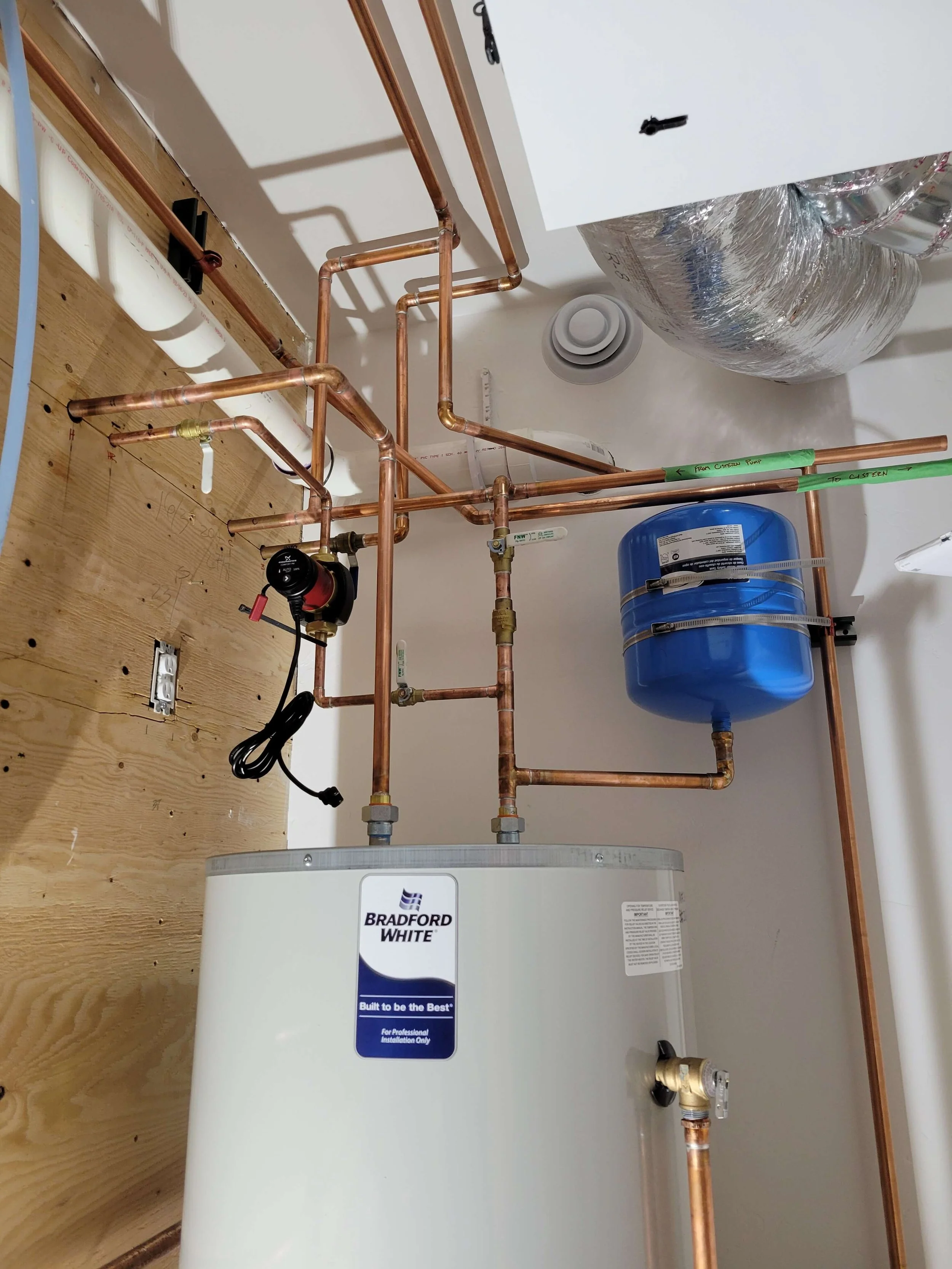 Hot water heater installation with copper pipes, expansion tank, and ductwork.