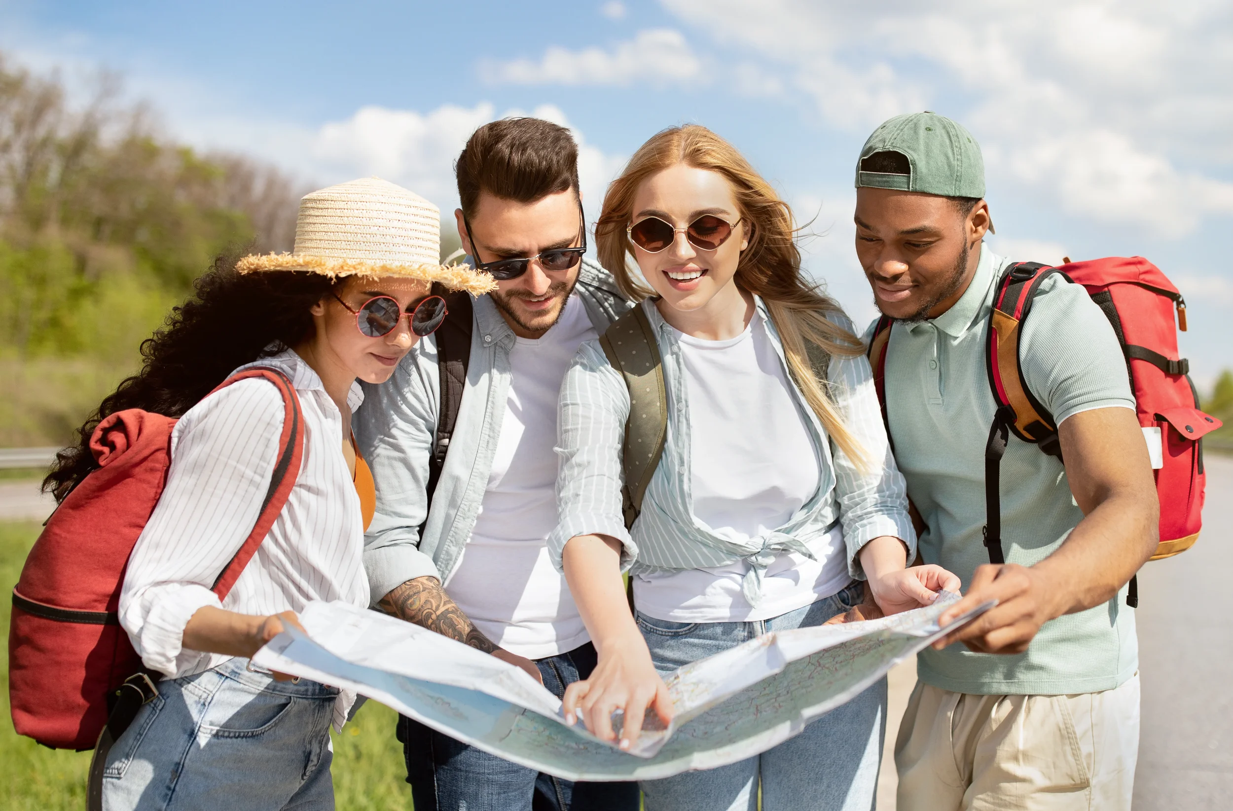 Four friends outdoors examining a map on a sunny day