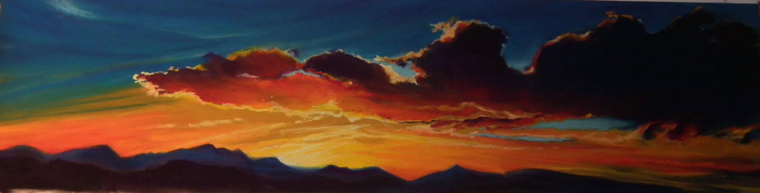 Colorful sunset sky with vibrant orange, pink, and purple clouds over silhouettes of mountains.