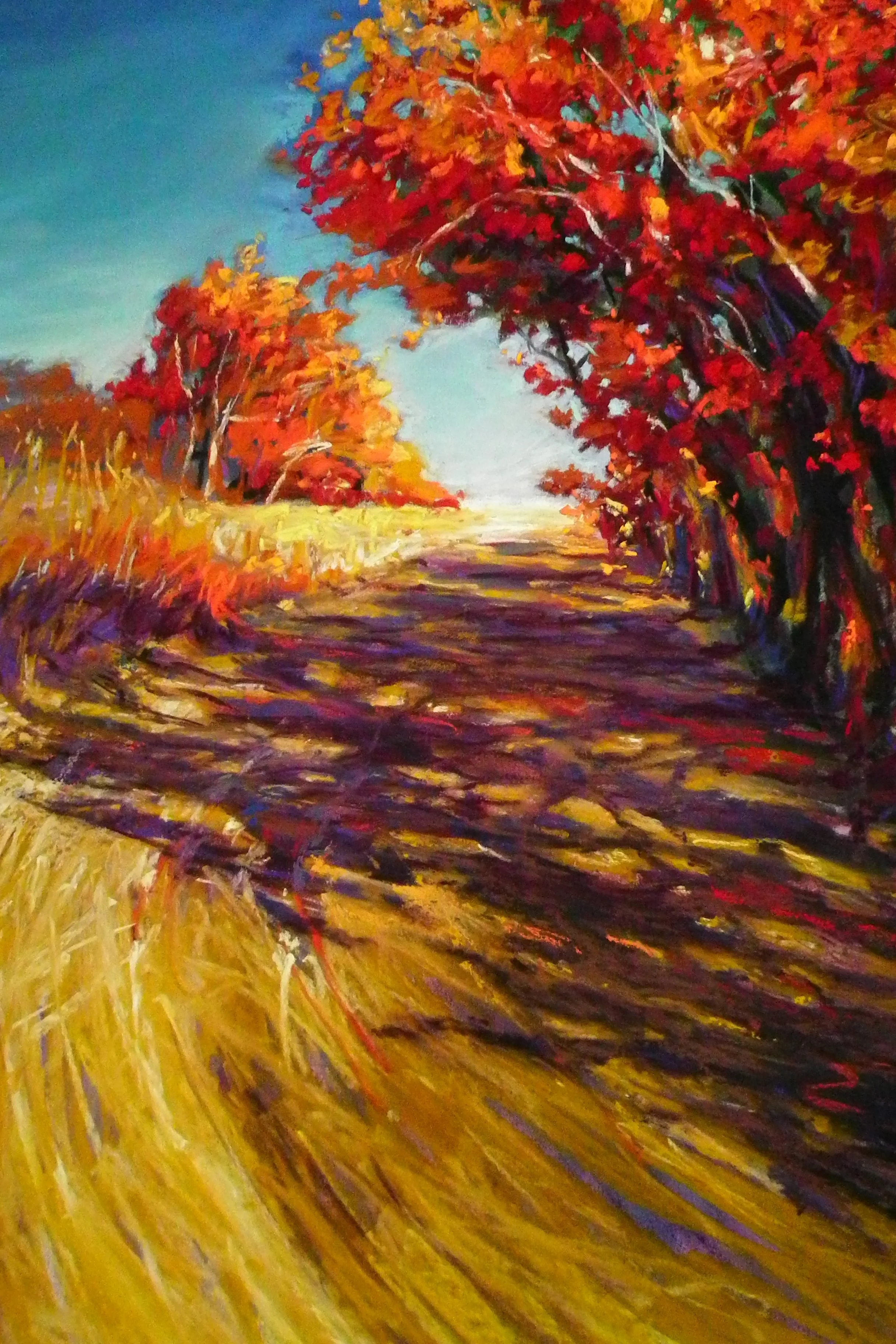 An impressionist painting of a rural landscape with a dirt path running through tall, golden grass about to the colorful red and orange trees on either side. The sky is bright blue with hints of clouds.