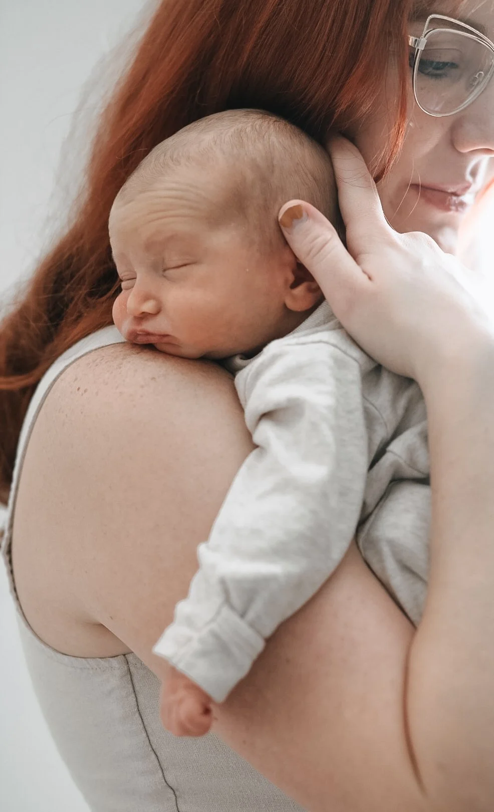 Newborn sleeping on woman's shoulder indoors.