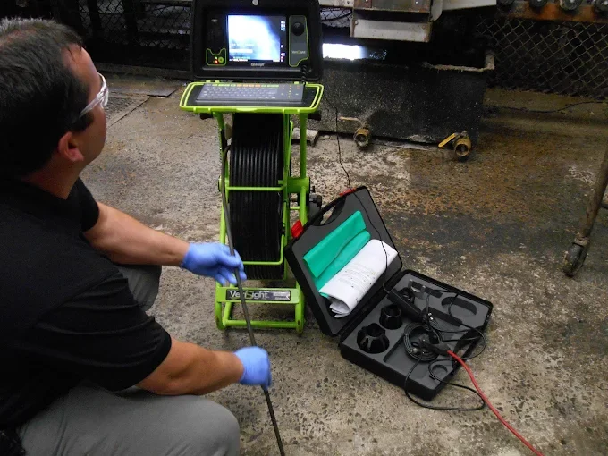 A technician wearing gloves and safety glasses inspecting a drain line for a client in Nova Scotia.
