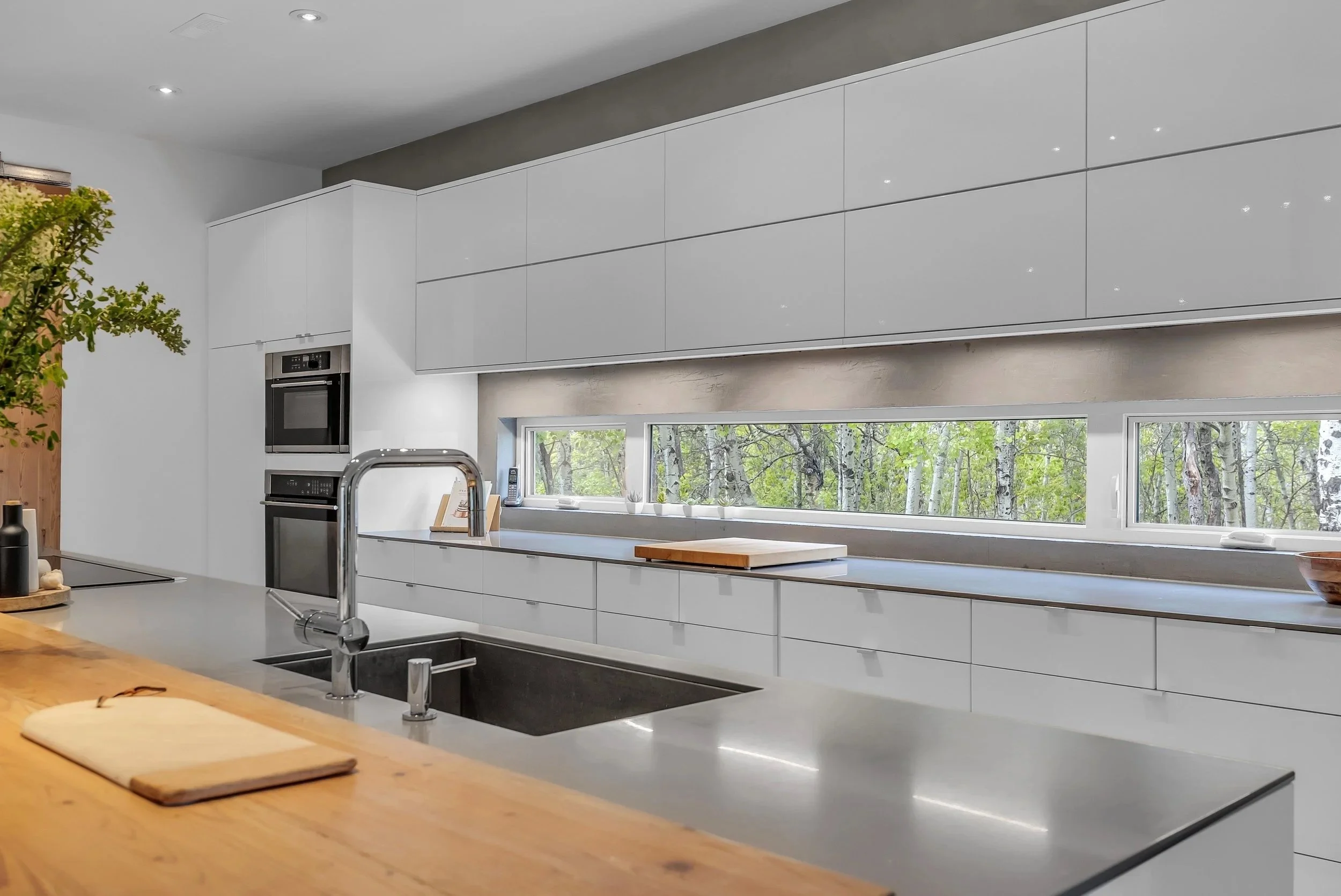 Modern kitchen with clean lines, warm finishes, and forest views.